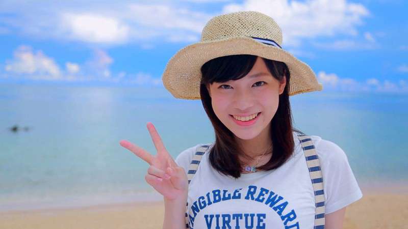 麻宮まどかがビーチをバックにムギワラ帽子をかぶり笑顔